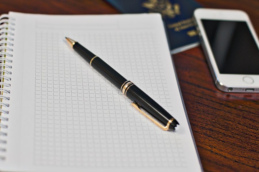 A grid-paper notebook and pen resting on a wooden desk.