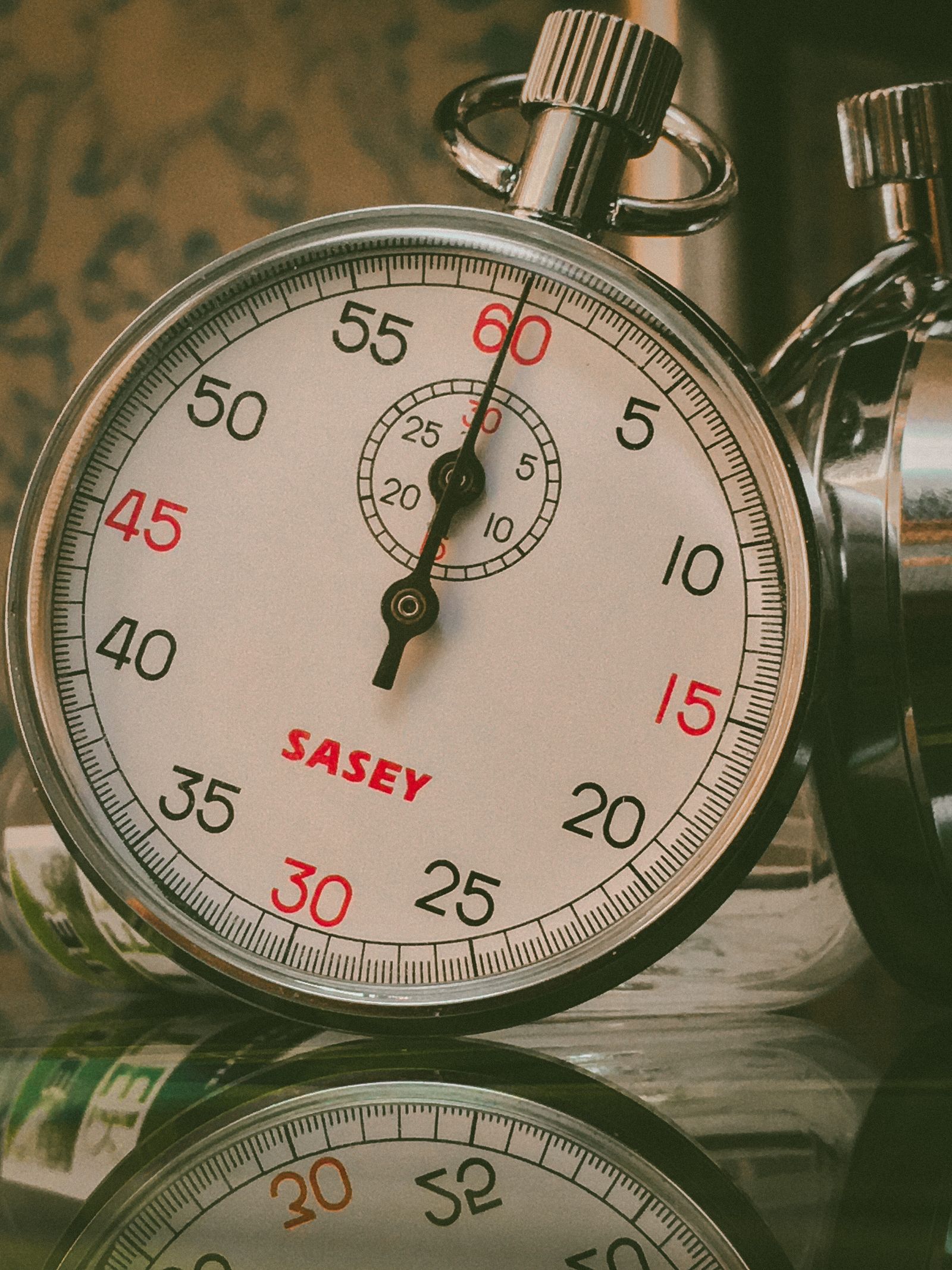 A vintage analog stopwatch resting on a reflective dark surface.