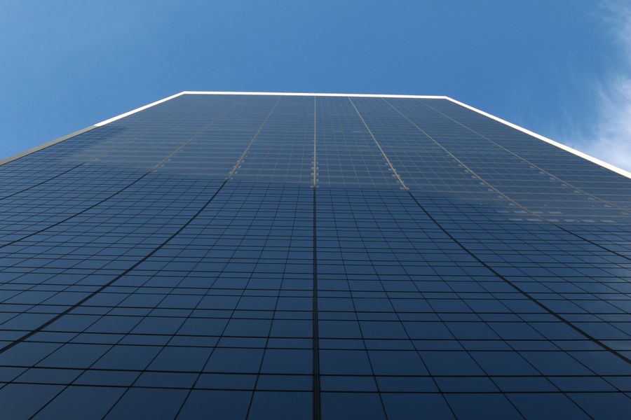Low angle view of a glass-fronted office tower against a clear sky.