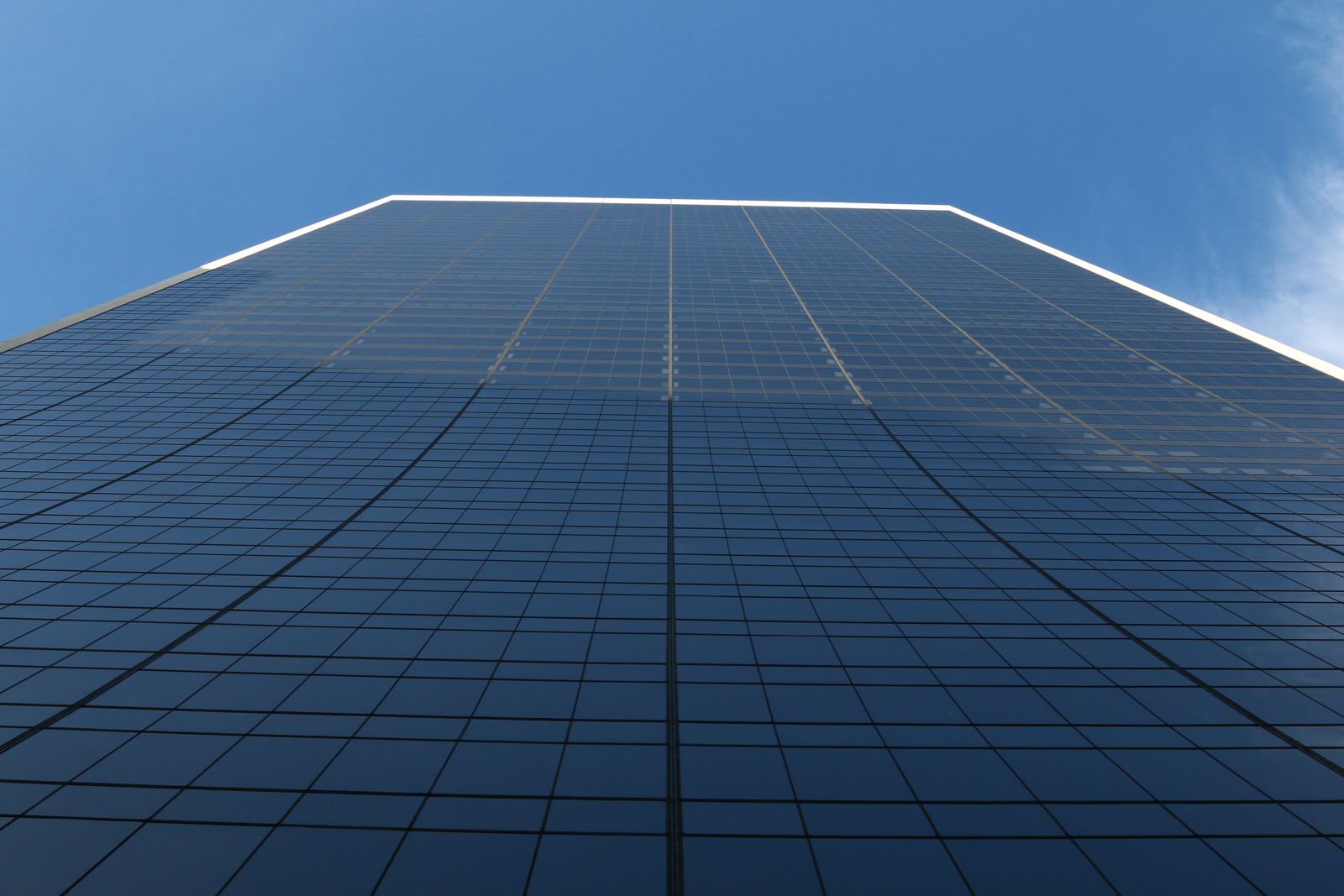 Low angle view of a glass-fronted office tower against a clear sky.