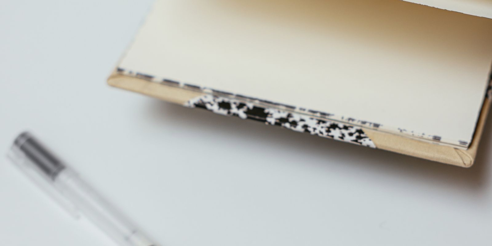 A grid-paper notebook and pen resting on a wooden desk.