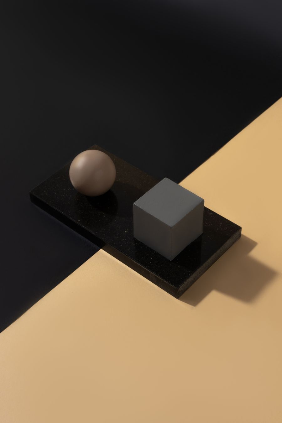 A minimalist still life of two geometric forms on a split background.
